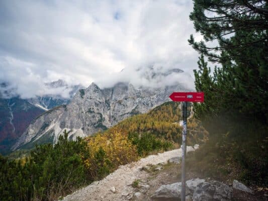 Panneau de signalisation de sentier de cabane de montagne avec un paysage de montagne en arrière-plan.